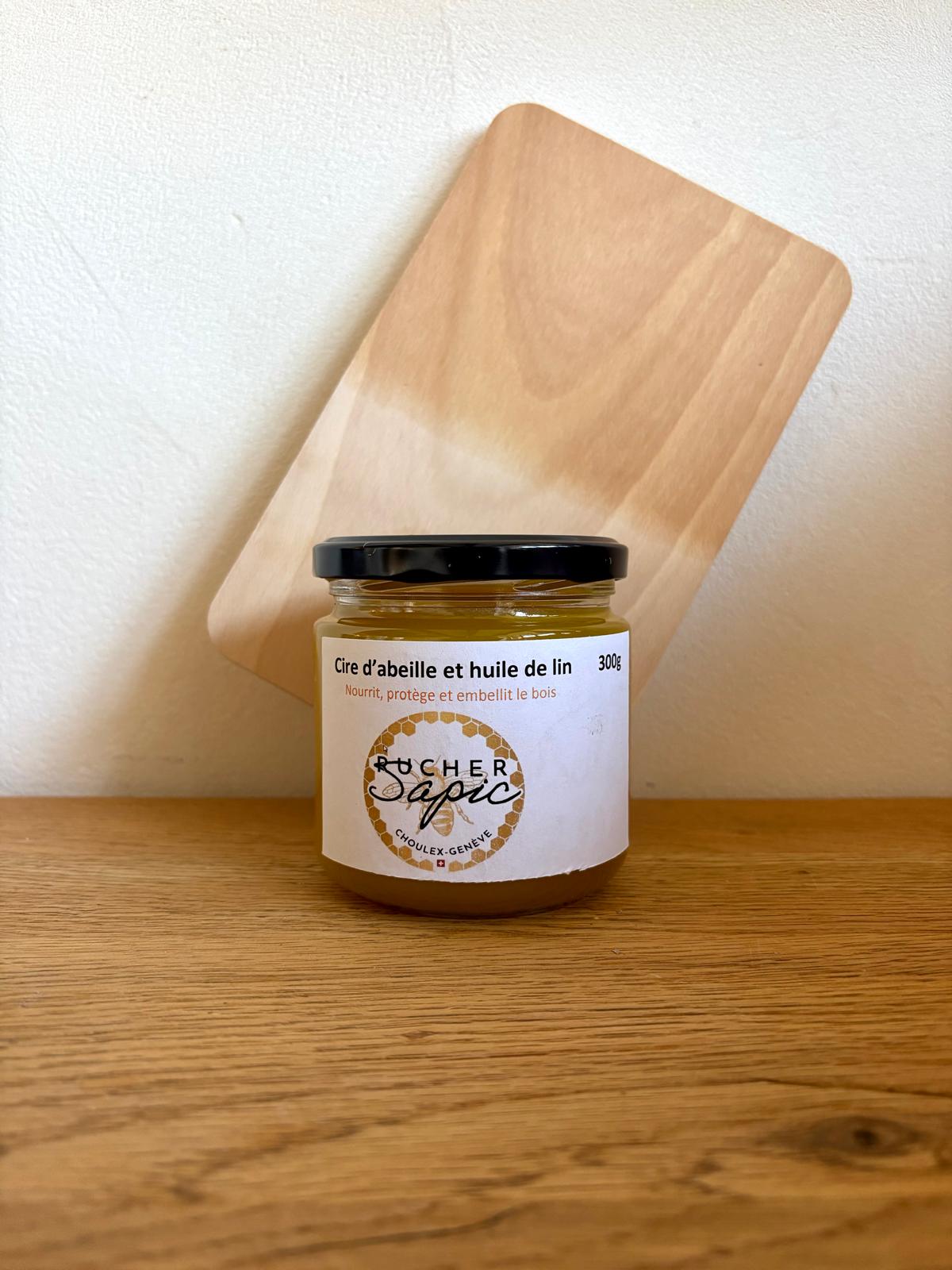 Pot de cire d’abeille et huile de lin du Rucher SAPIC, 300g, devant une planche à découper en bois